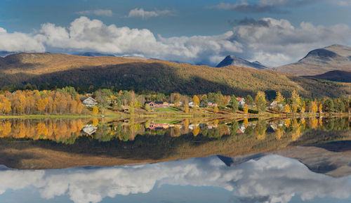 Beautiful scenic landscape with mountain and autumnal forest reflecting in water in norway.