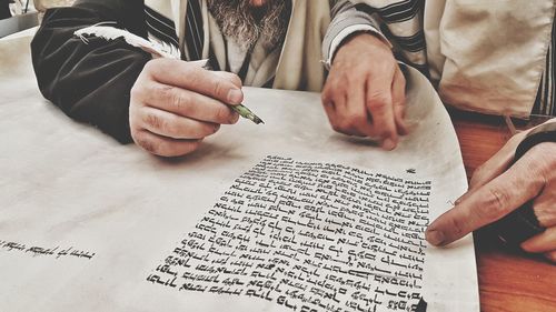 Midsection of man reading book on table