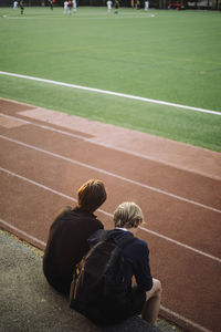 Rear view of teenage boys sitting while watching soccer match