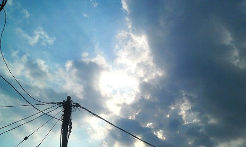 Low angle view of power lines against cloudy sky