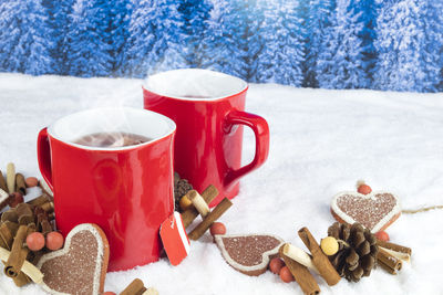 Close-up of coffee cups with christmas decoration on snow
