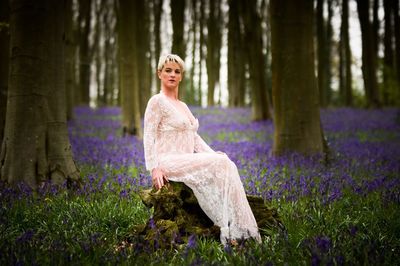 Young woman standing by purple flowers in forest