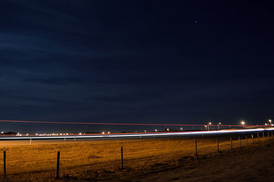 Light trails over field against sky at night