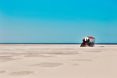 Lifeguard hut on beach against clear blue sky