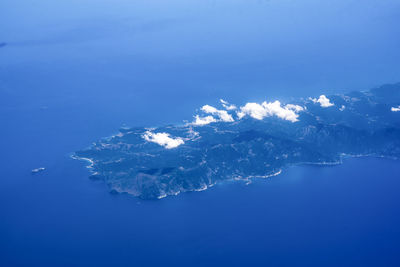 Aerial view of island amidst sea against blue sky