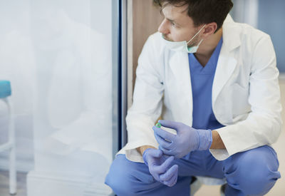 Doctor looking away while crouching at hospital