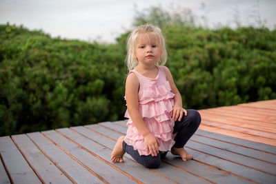 Full length portrait of cute girl kneeling on floorboard