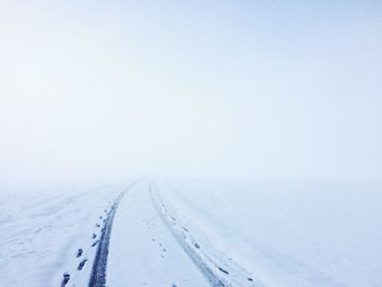 Snow covered road amidst landscape against sky