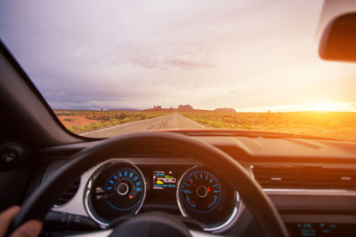 Close-up of hand on car against sky during sunset