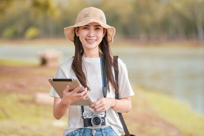 Portrait of smiling young woman using mobile phone outdoors