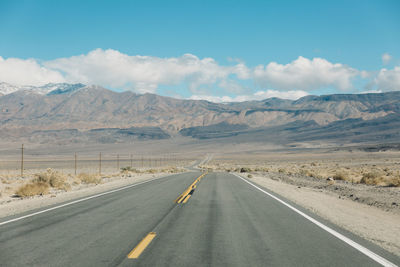 Empty road by mountains against sky