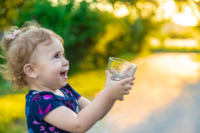 Cute girl holding drinking water at public park