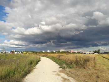 Road amidst agricultural field against sky