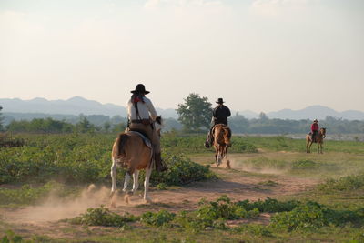 People riding horses on land against sky