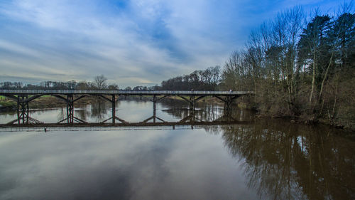 Bridge over river against cloudy sky