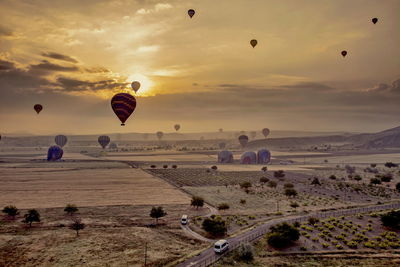 Hot air balloons flying over land during sunset