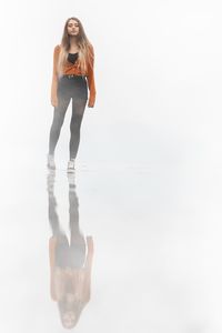 Full length of young woman standing on white background