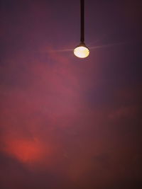 Low angle view of illuminated light bulb against sky at sunset