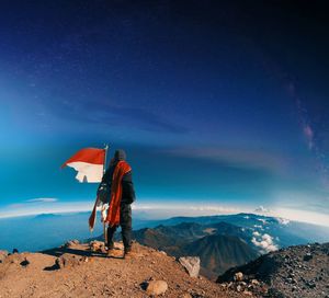 Rear view of man on mountain against sky at night