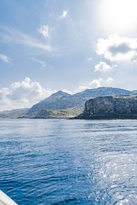 Scenic view of sea by mountains against sky