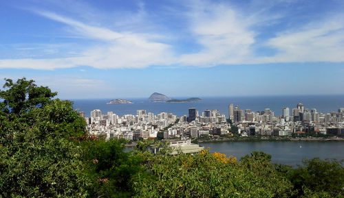 City at waterfront against cloudy sky