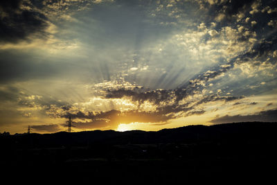 Silhouette landscape against dramatic sky during sunset