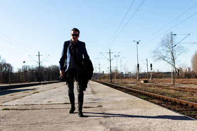 Man standing on railroad track against sky