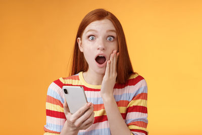Portrait of mid adult woman using smart phone against orange background