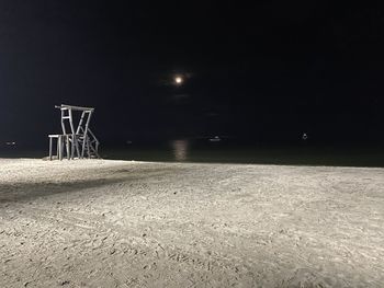Illuminated street light on field against sky at night
