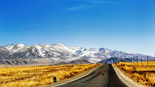 Road by mountains against clear blue sky