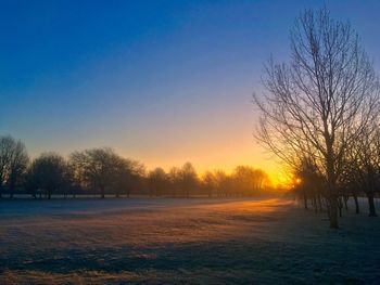 Snow covered field against sky during sunset