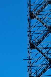 Low angle view of rollercoaster against clear blue sky