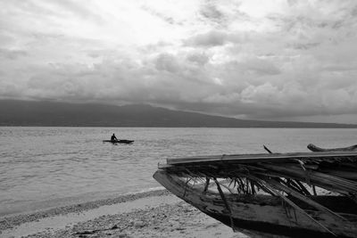 Boats in sea against cloudy sky