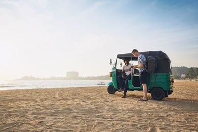 Men talking by rickshaw at beach