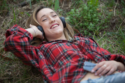 High angle view of woman listening music while lying on field