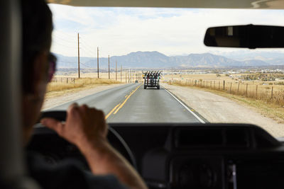 A view of the road mountains and a truck in front of us full of bikes.