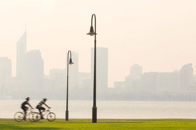 People riding bicycle on street against buildings in city