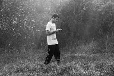 Side view of man using smart phone walking on grass