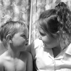 Close-up of siblings looking at each other at home