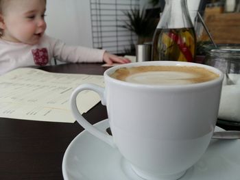 Close-up of man drinking coffee cup on table