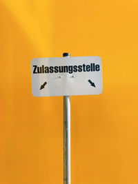 Low angle view of road sign against yellow background