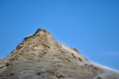 Low angle view of rock formation against clear blue sky