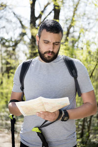 Hiker holding map while standing in forest