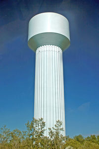 A white water tower with blue sky