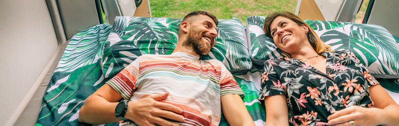 Couple looking at each other lying on the bed of their camper van