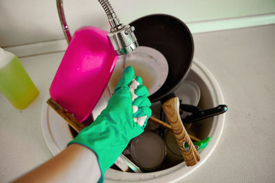 Cropped hand of woman wearing glove holding cleaning sponge