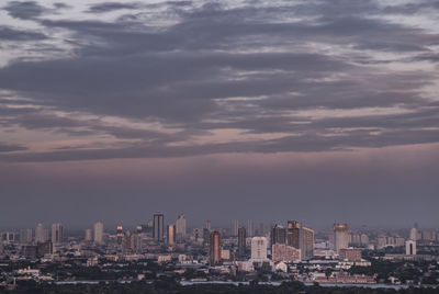 Modern buildings in city against sky during sunset