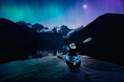 Rear view of person on snowcapped mountains against sky at night