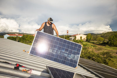 Construction worker prepares to install a solar panel on roof.