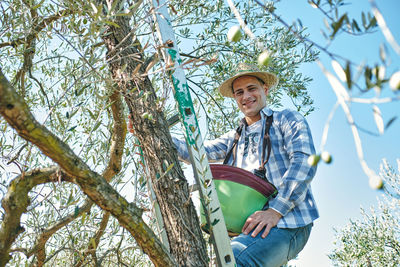 Low angle view of young woman standing against plants